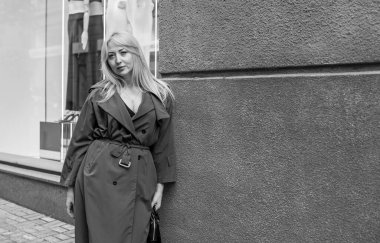 Gri ceketli olgun Avrupalı sarışın kadın şehir merkezinde yürüyor, modaya uygun trendler.