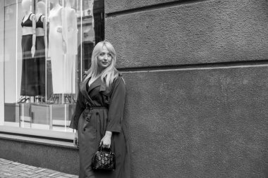 Gri ceketli olgun Avrupalı sarışın kadın şehir merkezinde yürüyor, modaya uygun trendler.