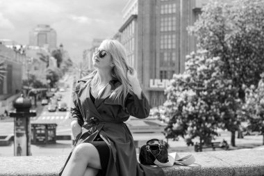 Gri ceketli olgun Avrupalı sarışın kadın şehir merkezinde yürüyor, modaya uygun trendler.