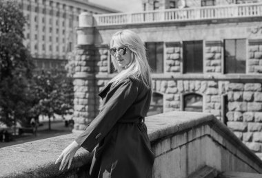 Gri ceketli olgun Avrupalı sarışın kadın şehir merkezinde yürüyor, modaya uygun trendler.