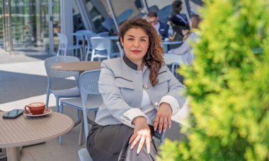 Şehir merkezindeki iş dünyasında kıvırcık saçlı neşeli Latin Kadın.
