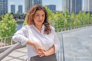 Şehir merkezindeki iş dünyasında kıvırcık saçlı neşeli Latin Kadın.