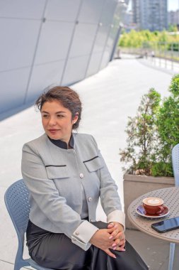 Şehir merkezindeki iş dünyasında kıvırcık saçlı neşeli Latin Kadın.
