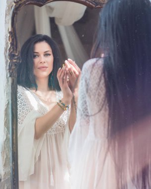 Esmer bir kadın, bembeyaz bir elbise, zarafet portresi, dayanıklılık ve güzellik sarılmış, sabah ışığında sessizce durur 