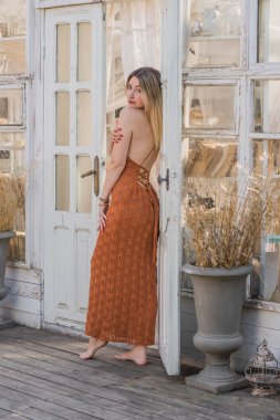 Terasta uzun örgü elbiseli sarışın kadın, Boho tarzı, modern trendler.