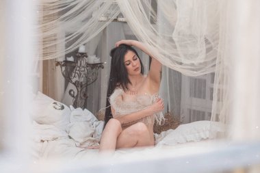 Yatak odasında modern bir bayan. Duygusallık konsepti, seksi vücutlu tatlı bayan klasik pastel iç mekan.