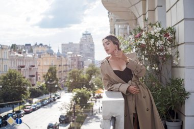 Bej ceketli, çoraplı ve siyah iç çamaşırlı bir kadın. Avrupalı sarışının balkondaki şehvetli fotoğrafı..