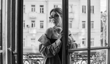 Bej ceketli, çoraplı ve siyah iç çamaşırlı bir kadın. Avrupalı sarışının balkondaki şehvetli fotoğrafı..