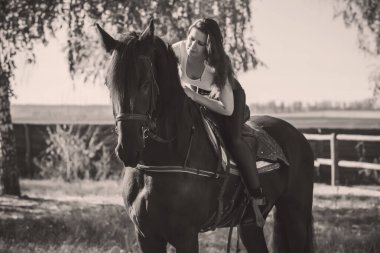 Ata binen zarif bir kadın atıyla konuşuyor. Bir kadınla ata binmenin portresi. Doğası gereği binicisi olan bir at.