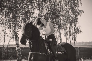 Ata binen zarif bir kadın atıyla konuşuyor. Bir kadınla ata binmenin portresi. Doğası gereği binicisi olan bir at.