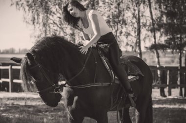 Ata binen zarif bir kadın atıyla konuşuyor. Bir kadınla ata binmenin portresi. Doğası gereği binicisi olan bir at.