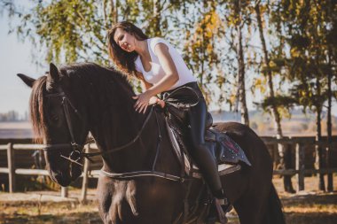 Ata binen zarif bir kadın atıyla konuşuyor. Bir kadınla ata binmenin portresi. Doğası gereği binicisi olan bir at.