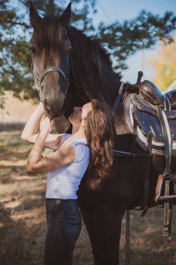 Ata binen zarif bir kadın atıyla konuşuyor. Bir kadınla ata binmenin portresi. Doğası gereği binicisi olan bir at.