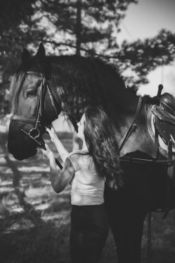 Ata binen zarif bir kadın atıyla konuşuyor. Bir kadınla ata binmenin portresi. Doğası gereği binicisi olan bir at.