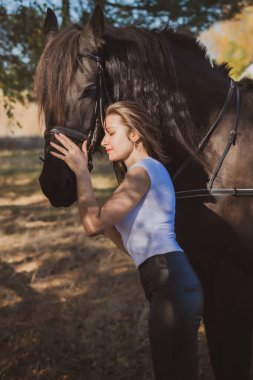 Ata binen zarif bir kadın atıyla konuşuyor. Bir kadınla ata binmenin portresi. Doğası gereği binicisi olan bir at.