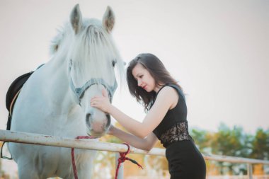 Kadınlık kavramı. Siyah elbiseli genç bir kadın ve bir at. Siyah atlı güzel kız.