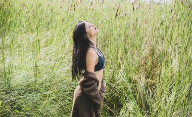 Uzun saçlı çingene kız doğaya poz veriyor. İnce vücutlu, atletik vücutlu, örgü kazaklı, seksi bir hırka giymiş, klasik bir kadın.