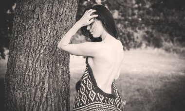 Uzun saçlı çingene kız doğaya poz veriyor. İnce vücutlu, atletik vücutlu, örgü kazaklı, seksi bir hırka giymiş, klasik bir kadın.