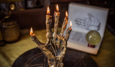 Sihirli sunak, yanan mum, mistik el ve altın kumaş üzerinde antik büyü kitabı.