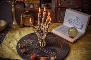 Sihirli sunak, yanan mum, mistik el ve altın kumaş üzerinde antik büyü kitabı.