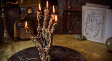 Sihirli sunak, yanan mum, mistik el ve altın kumaş üzerinde antik büyü kitabı.