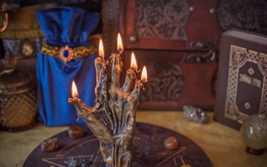 Sihirli sunak, yanan mum, mistik el ve altın kumaş üzerinde antik büyü kitabı.