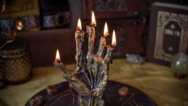 Sihirli sunak, yanan mum, mistik el ve altın kumaş üzerinde antik büyü kitabı.