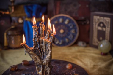 Sihirli sunak, yanan mum, mistik el ve altın kumaş üzerinde antik büyü kitabı.