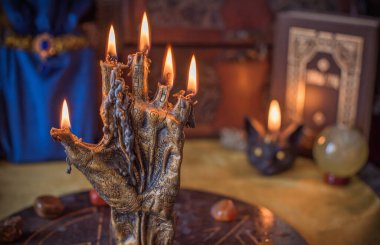 Sihirli sunak, yanan mum, mistik el ve altın kumaş üzerinde antik büyü kitabı.