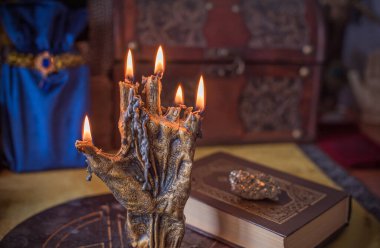 Sihirli sunak, yanan mum, mistik el ve altın kumaş üzerinde antik büyü kitabı.