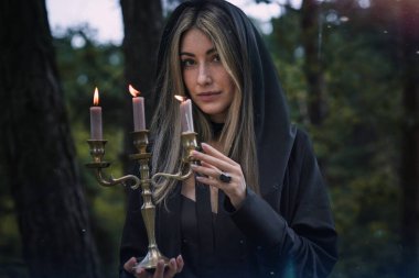 Siyah Pelerinli Zarif Gri Saçlı Cadı Gizemli Ormanda Mum Tutuyor