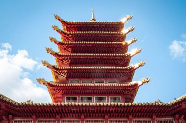 Simetrik çok katmanlı kırmızı pagoda çatısı altın süslemeler, ejderha kafaları ve kule ile süslenmiş. Budist tapınağı