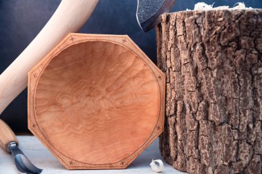 A plate with an ornament carved with an axe and chisel, placed next to it and a log with shavings clipart