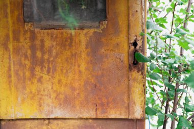 Yıpranmış bir elektrik kutusunun yakın çekimi paslı yüzeyi çürümenin güzelliğini ortaya çıkarıyor. Kilit ve etrafındaki aşınma, zamanın geçişini ve endüstriyel nesnelerin kırılganlığını hatırlatıyor.