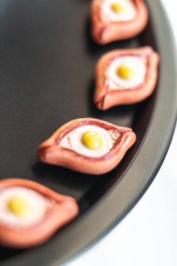 Khachapuri mıknatıslarının yakın plan görüntüsü siyah bir tepside, Gürcü mutfak ikonunun canlı renklerini ve sanatsal tasarımını vurguluyor.