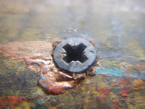 Siyah arkaplanı olan paslı metal bir delik.