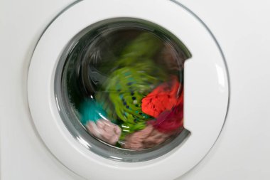 Çamaşır makinesi renkli giysileri yıkıyor, kapat.