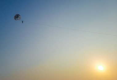 Parasailing ekstrem sporları mavi arka planda plajda. İnsanlar mavi gökyüzünde paraşütle atlıyor. Denizin üstündeki açık gökyüzünde paraşütle atlıyor..