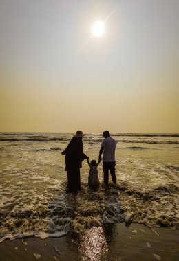 Aile Yürüyüşü Sahil Günbatımı Seyahat Tatil Konsepti. Ebeveynler ve kızları aktif bir aile tatilinde sahilde yürüyorlar..