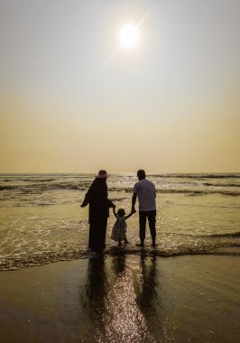 Aile Yürüyüşü Sahil Günbatımı Seyahat Tatil Konsepti. Ebeveynler ve kızları aktif bir aile tatilinde sahilde yürüyorlar..