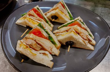 Jambonlu sandviç, peynir, domates, marul, tavuk eti ve kızarmış ekmek. Sandviç masada..