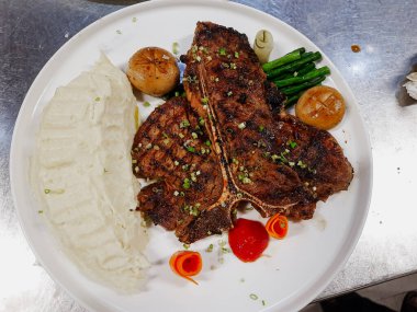 Izgara et tabağı. Pişmiş biftek, sebzeli biftek ve taze sebze. Yumuşak ızgara biftek ya da patates püresi ve ızgara mantarla servis edilen biftek..