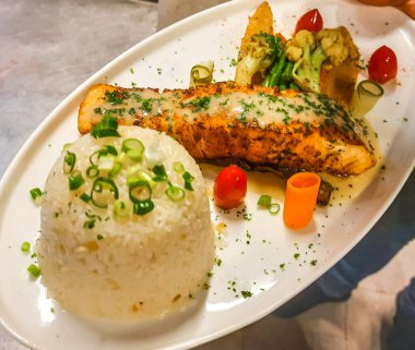 Limon soslu ızgara somon, acı biber taneleri ve kızarmış sarımsaklı pilav. Lezzetli somon bifteği, karabiber ve sarımsaklı pilav..