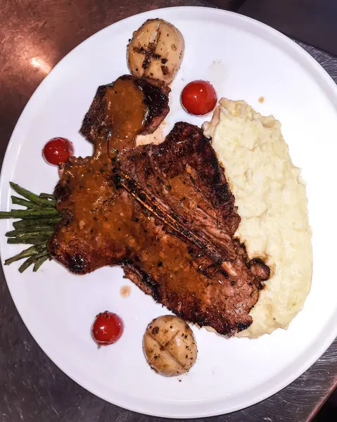 Izgara et tabağı. Pişmiş biftek, sebzeli biftek ve taze sebze. Yumuşak ızgara biftek ya da patates püresi ve ızgara mantarla servis edilen biftek..