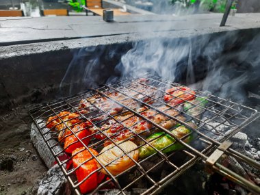 Izgarada, dumanlı ve alevli çeşit çeşit ızgara et. Barbekü şişleri yanan ızgarada sebzeli et kebabı.