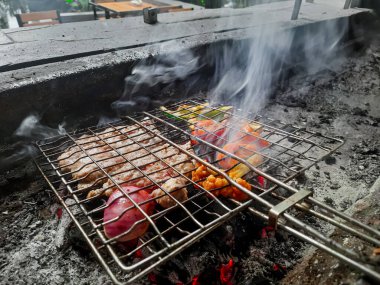 Izgarada, dumanlı ve alevli nefis ızgara et. Barbekü şişleri yanan ızgarada sebzeli et kebabı.