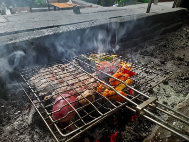 Izgarada, dumanlı ve alevli nefis ızgara et. Barbekü şişleri yanan ızgarada sebzeli et kebabı.