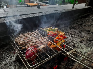 Izgarada, dumanlı ve alevli nefis ızgara et. Barbekü şişleri yanan ızgarada sebzeli et kebabı.