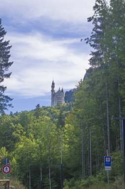 Neuschwanstein, ünlü masal kalesi, prensesler ve sevgililer, mavi gökyüzüne ve ormanlara karşı durur göllerin arka planına karşı