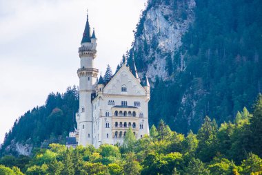 Neuschwanstein, ünlü masal kalesi, prensesler ve sevgililer, mavi gökyüzüne ve ormanlara karşı durur göllerin arka planına karşı